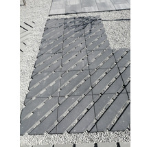 Gehweg aus diagonal verlegten Betonpflastersteinen mit Fugen auf einer Kiesfläche im Außenbereich