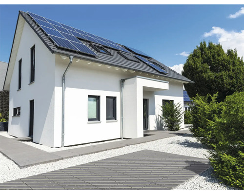Einfamilienhaus mit Solaranlage auf dem Dach und modern gestaltetem Garten mit gepflastertem Weg und Kiesbeet.