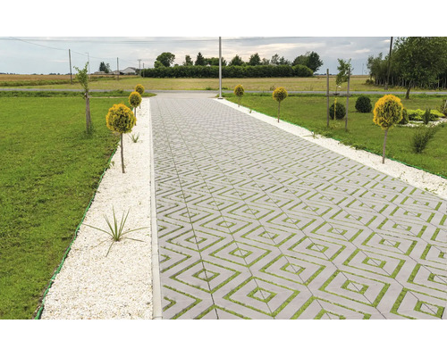 Gepflasterte Auffahrt mit quadratischen Rasengittersteinen in einem Gartenbereich mit Rasenfläche und Ziersträuchern.