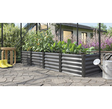 Rechteckiges Hochbeet aus Metall in einem Gewächshaus bepflanzt mit Tomaten und Salat auf einer gepflasterten Terrasse im Garten.