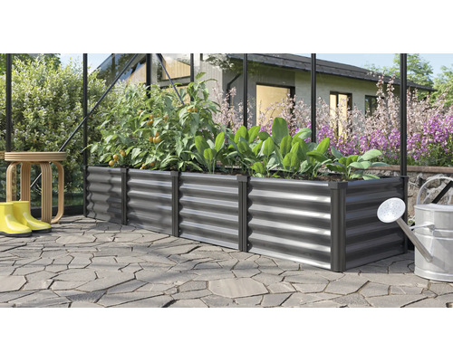 Rechteckiges Hochbeet aus Metall in einem Gewächshaus bepflanzt mit Tomaten und Salat auf einer gepflasterten Terrasse im Garten.