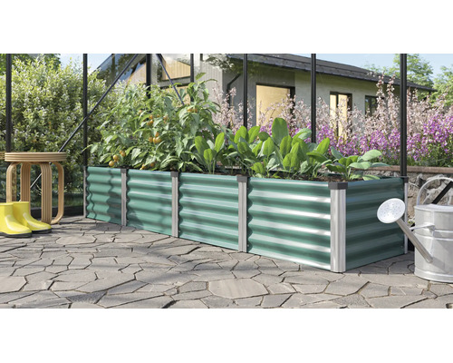 Rechteckiges Hochbeet aus Metall mit gewellter Struktur bepflanzt mit Tomaten und Salat in einem Gewächshaus auf einer gepflasterten Terrasse.