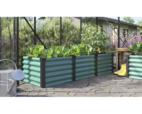 Rechteckiges Hochbeet aus Metall mit Wellenstruktur in einem Gewächshaus mit Pflanzen und Gartenutensilien auf einer Terrasse.