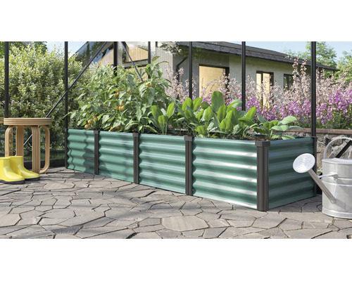 Rechteckiges Hochbeet aus Metall mit Wellenstruktur in einem Gewächshaus mit Pflanzen und Gartenutensilien