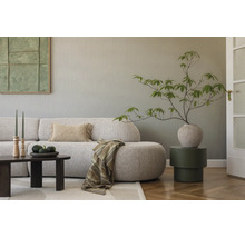 Modernes Wohnzimmer mit strukturierter Tapete, geschwungenem Sofa, dunklem Couchtisch, Beistelltisch und Zimmerpflanze in Vase.