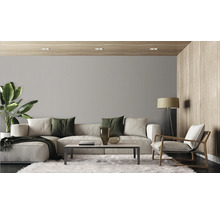 Modernes Wohnzimmer mit strukturierter Tapete, großem Sofa, Sessel, Couchtisch und Zimmerpflanze in einer organischen Einrichtung.