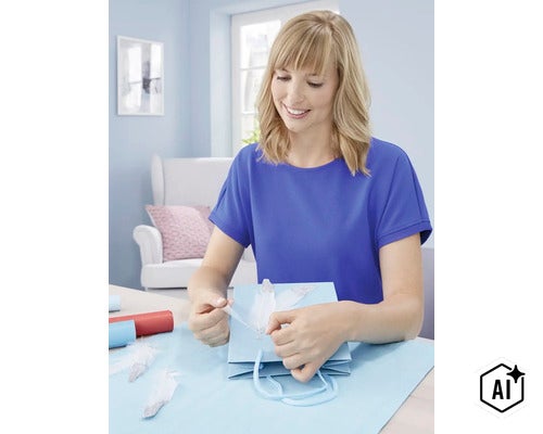 Eine Frau beim Verpacken eines Geschenks mit einer Geschenktüte und dekorativen Federn in einem hell eingerichteten Raum. (Image AI modified or generated)