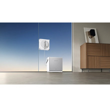 Ein elektrischer Fensterreinigungsroboter reinigt eine große Fensterscheibe, verbunden mit einer Basisstation auf dem Boden in einem modernen Raum.