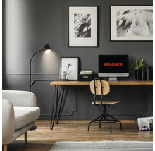 Modernes Arbeitszimmer mit Briloner Logo auf dem Monitor, Schreibtisch aus Holz, Drehstuhl und Stehleuchte vor einer Wand mit Wandpaneelen.