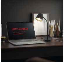 Schreibtischlampe mit flexiblem Arm auf einem Arbeitsplatz mit Laptop und Briloner Logo auf dem Bildschirm