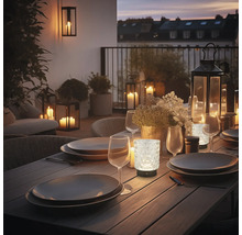 Tischleuchte aus Glas mit strukturierter Oberfläche als atmosphärische Beleuchtung auf einer gedeckten Terrasse am Abend.