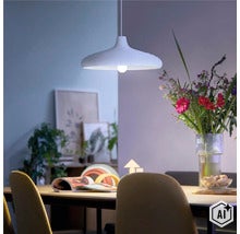 Moderne Hängeleuchte in einem wohnlichen Esszimmer über einem Holztisch mit Blumenstrauß in einer Glasvase. (Image AI modified or generated)