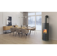 Moderner Kaminofen in einem hellen Esszimmer mit Holztisch und Stühlen vor einer Fensterfront mit Blick auf eine verschneite Winterlandschaft.