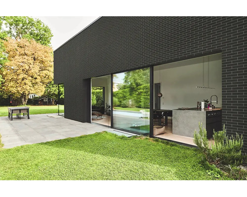 Moderne Villa mit dunkler Ziegelfassade und bodentiefen Schiebetüren zur Terrasse und in den offenen Wohnbereich mit moderner Küche.