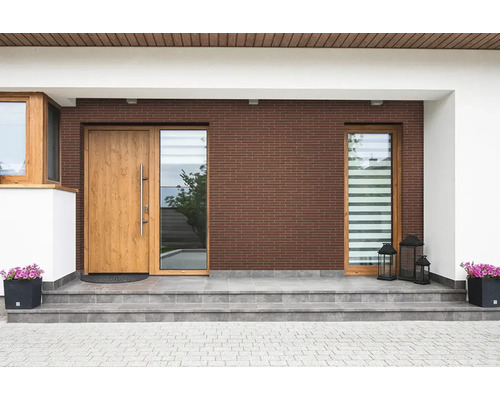 Moderne Hauseingangsgestaltung mit brauner Klinkerfassade, Holztür, Seitenteil und grauen Fliesentreppenstufen sowie Pflanzkübeln.
