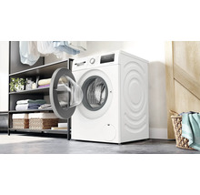 Bosch Waschmaschine mit offener Tür in einem modernen Hauswirtschaftsraum mit offener Regalkonstruktion und Wäschekorb.