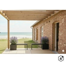 Überdachte Terrasse mit Holzkonstruktion vor einem Backsteinhaus mit Blick auf das Meer und zwei Pflanzkübeln mit lila Blumen und Sitzbänken. (Image AI modified or generated)