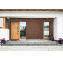 Moderne Hauseingangsgestaltung mit brauner Klinkerfassade, Holztür, Seitenteil und grauen Fliesentreppenstufen sowie Pflanzkübeln.
