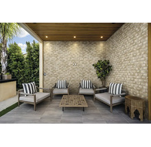Moderne überdachte Terrasse mit Verblendern in Ziegeloptik, Sitzgruppe aus Holzsesseln mit Kissen und quadratischem Couchtisch auf Fliesenboden.