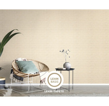 Eine Lehm Tapete mit Ziegelstein Optik in einem modern eingerichteten Wohnzimmer mit Rattan Sessel und Beistelltisch.