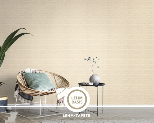 Eine Lehm Tapete mit Ziegelstein Optik in einem modern eingerichteten Wohnzimmer mit Rattan Sessel und Beistelltisch.