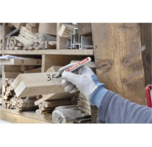 Person mit Arbeitshandschuh beschriftet Holzbalken mit einem Edding 3000 Permanentmarker in einem Holzlager.