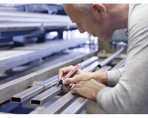 Handwerker markiert mit einem Edding 3000 Permanentmarker ein Metallprofil an einer Werkbank.