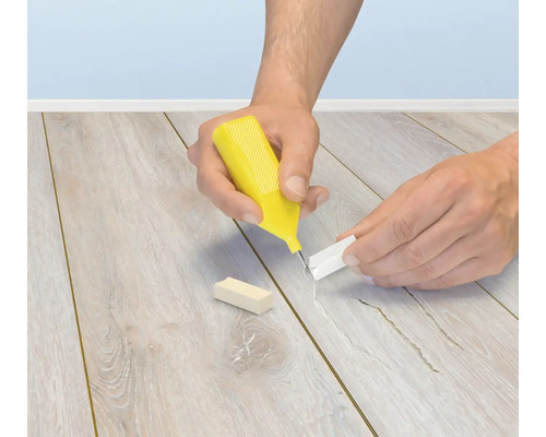 Person bei der Anwendung eines Reparatursets fuer Laminat und Parkett zur Ausbesserung von Fugen und Kratzern im Fussboden