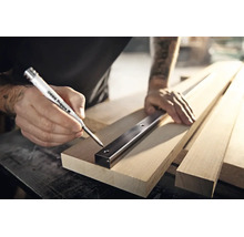 Handwerker markiert mit einem Edding 8880 Tieflochmarker Bohrlocher durch ein Metallprofil auf einem Holzbrett.