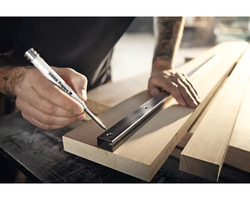 Handwerker markiert mit einem Edding 8880 Tieflochmarker Bohrlocher durch ein Metallprofil auf einem Holzbrett.