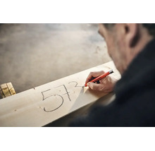 Handwerker markiert mit einem Edding 8850 Tieflochmarker Zahlen auf einem Holzbrett.