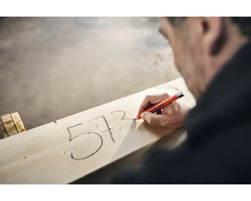Handwerker markiert mit einem Edding 8850 Tieflochmarker Zahlen auf einem Holzbrett.