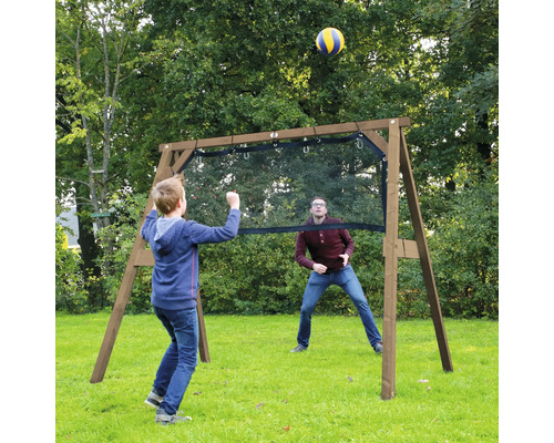 Kind und Erwachsener spielen Ball mit einem freistehenden Holzspielgerüst mit Netz im Garten.