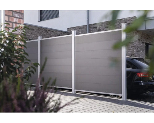 Moderner Sichtschutzzaun aus Kunststoff mit Metallpfosten als Abgrenzung vor einem Haus mit Auffahrt.
