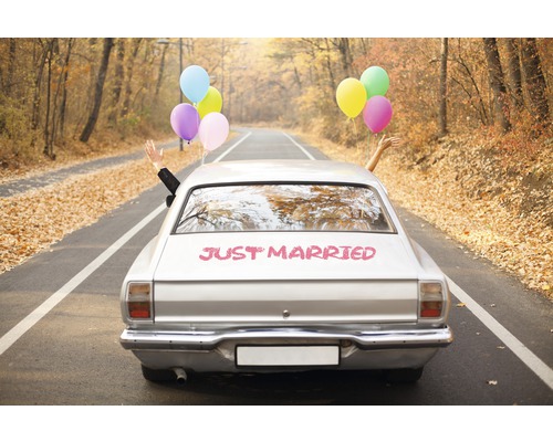 Silbernes Auto mit der Aufschrift frisch verheiratet und Luftballons auf einer Straße