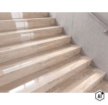 Treppe mit hochwertigen Stufenfliesen in Marmoroptik und profilierter Trittkante vor einer hellen Wand mit Handlauf. (Image AI modified or generated)