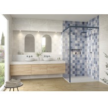 Helles Badezimmer mit Waschtisch, zwei Aufsatzwaschbecken, zwei Spiegeln und einer Duschkabine mit blau-weiß gemusterten Fliesen.