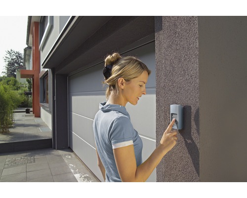 Frau bedient einen Taster für ein Garagentor.