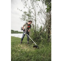 Mann benutzt einen Rasentrimmer im Garten, um das Gras zu schneiden.
