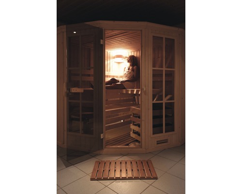 Frau entspannt in einer hellen Holzsauna mit Holzrost davor