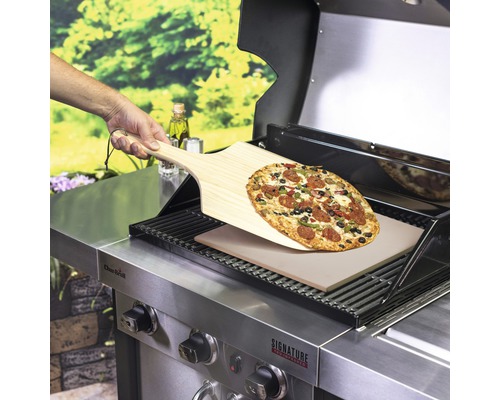 Eine Pizza auf einer Pizzaschaufel über einem Grill mit Pizzastein.