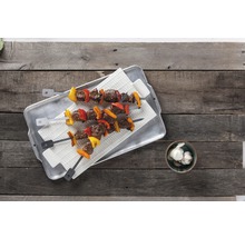Zwei Fleischspieße mit Paprika auf einem Tablett und Knoblauch in einer Schale