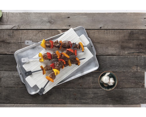 Zwei Fleischspieße mit Paprika auf einem Tablett und Knoblauch in einer Schale