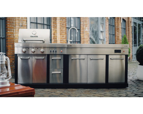 Outdoor-Küche mit Grill, Spüle und Schränken aus Edelstahl vor einer Backsteinmauer