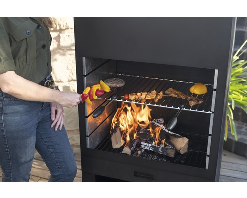 Frau grillt Gemüsespieße auf einem Holzkohlegrill.
