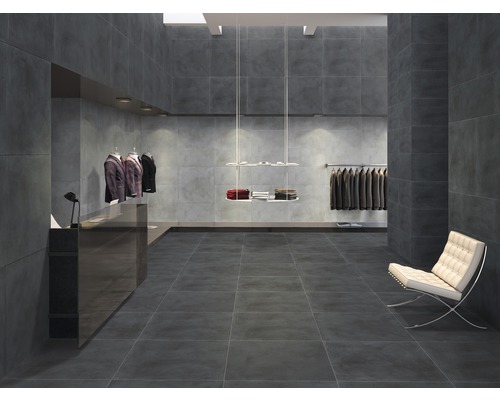 Heller Raum mit dunkelgrauen Fliesen an Boden und Wänden, Kleidern und einem Sessel