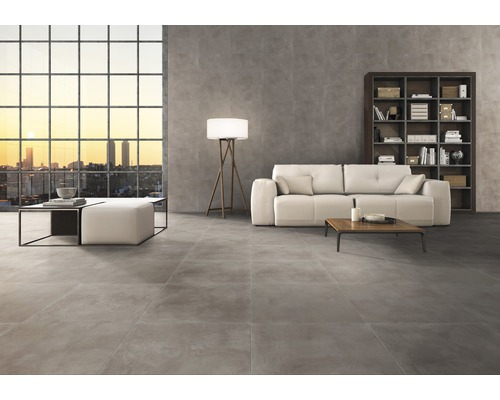 Heller Wohnraum mit grauen Bodenfliesen, Sofa, Bücherregal und großem Fenster