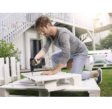 Mann arbeitet mit einem Akkuschrauber an einem DIY-Projekt aus Paletten im Garten.