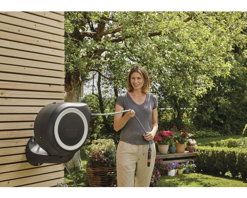 Frau benutzt eine automatische Schlauchbox im Garten