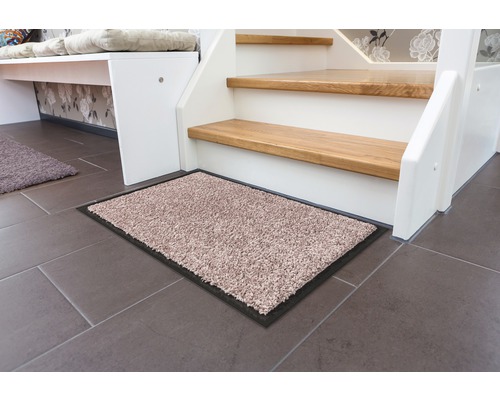 Schmutzfangmatte vor einer Treppe auf Fliesenboden.